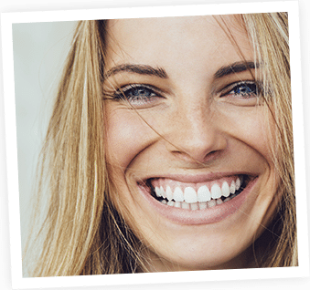 Woman with blonde hair smiling brightly at camera, close-up portrait against neutral background.