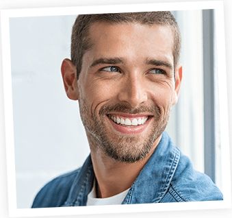 Smiling man in denim shirt against white background, professional headshot portrait.