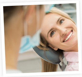 Smiling woman wearing headphones around neck in casual indoor setting, looking at camera.