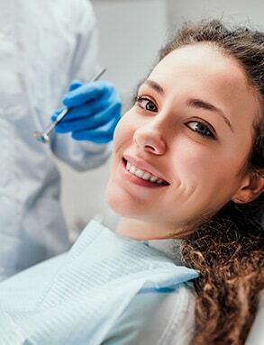 Smiling patient receiving dental treatment from dentist in blue gloves.