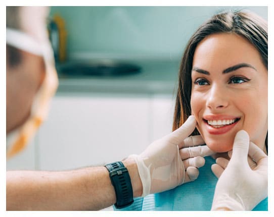 Dentist examining patient's teeth and jaw in clinical dental office setting.