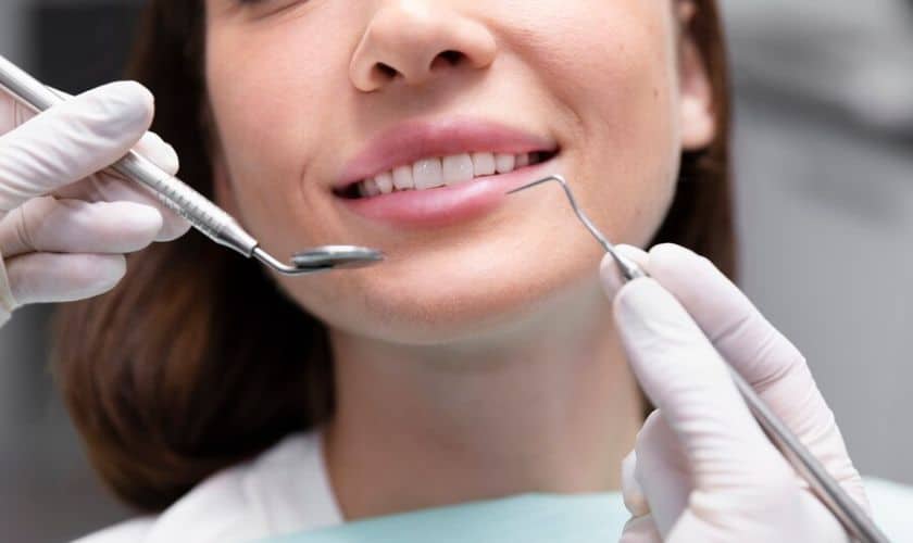 Dentist examining patient's teeth with dental instruments during oral checkup.