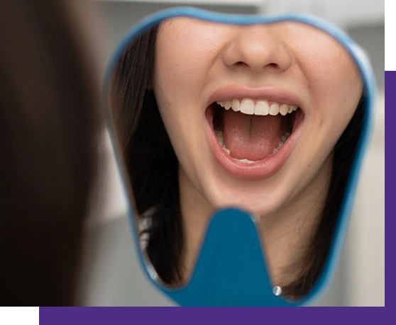 Woman wearing blue hoodie laughing with mouth wide open indoors.